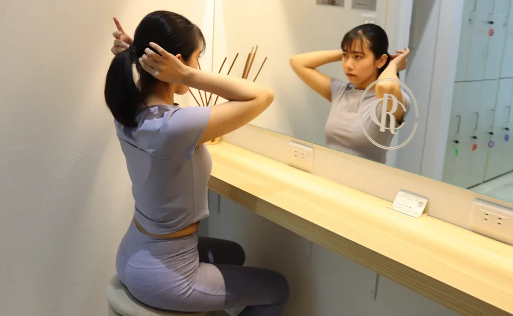 ピラティススタジオのパウダールームで髪を整える女性