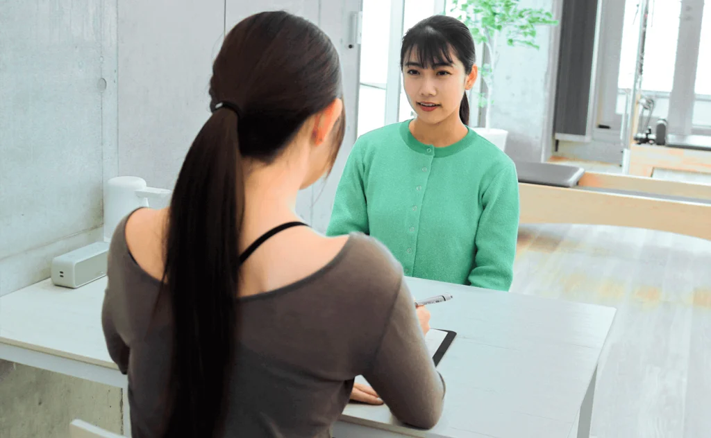 ピラティス体験レッスン前のカウンセリングでインストラクターと話す女性