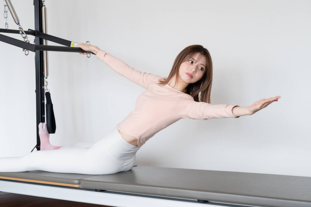 韓国式マシンピラティスでストレッチポーズを取る女性(キャデラックマシンを使用)